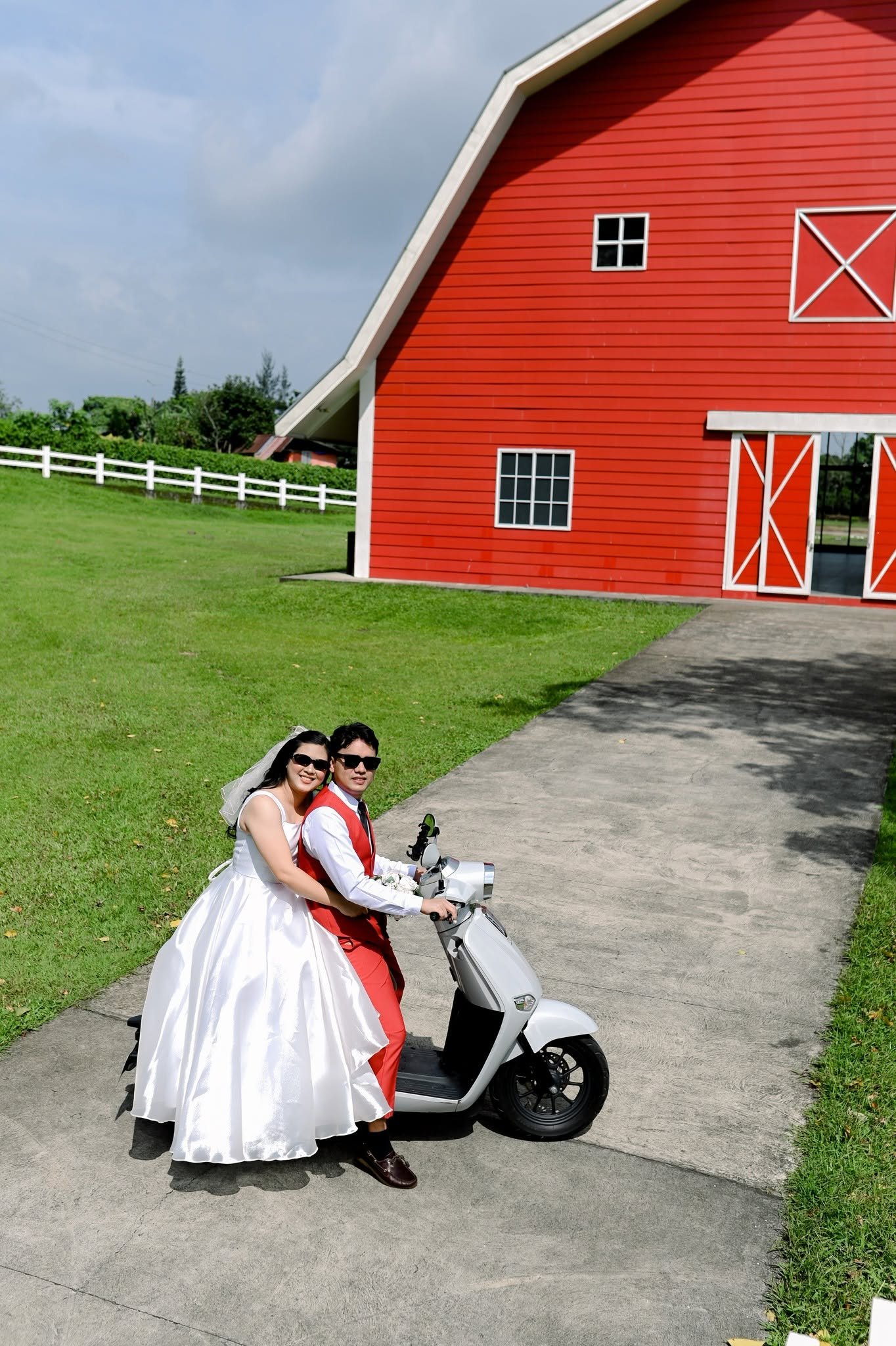 Chie and Cath on a scooter beside the red barn.